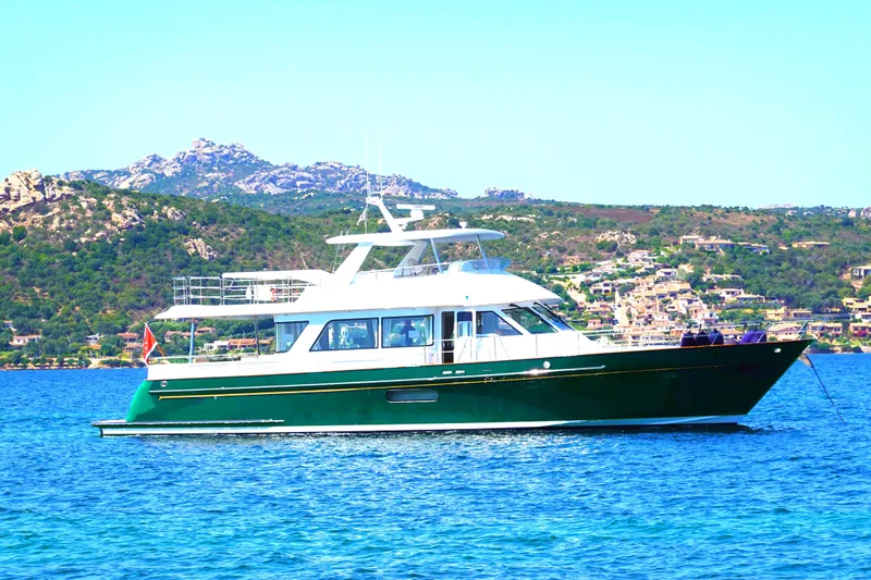 Frivolous Yacht Photos Pics 2019 Hunt Yachts Motor Yacht on scenic coastal waters with mountainous backdrop.
