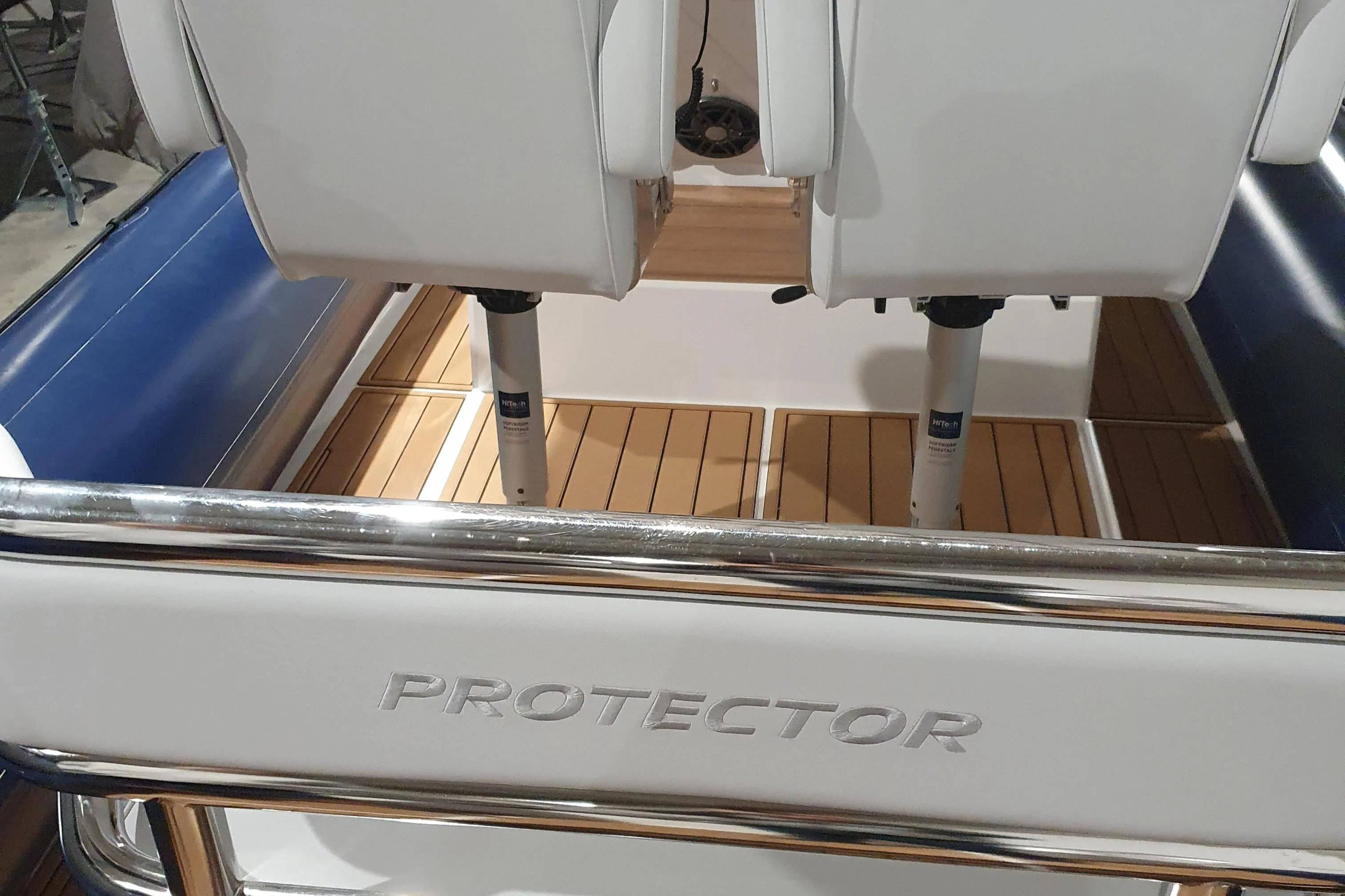 2023 Protector 330 boat interior with white seats and wooden flooring.