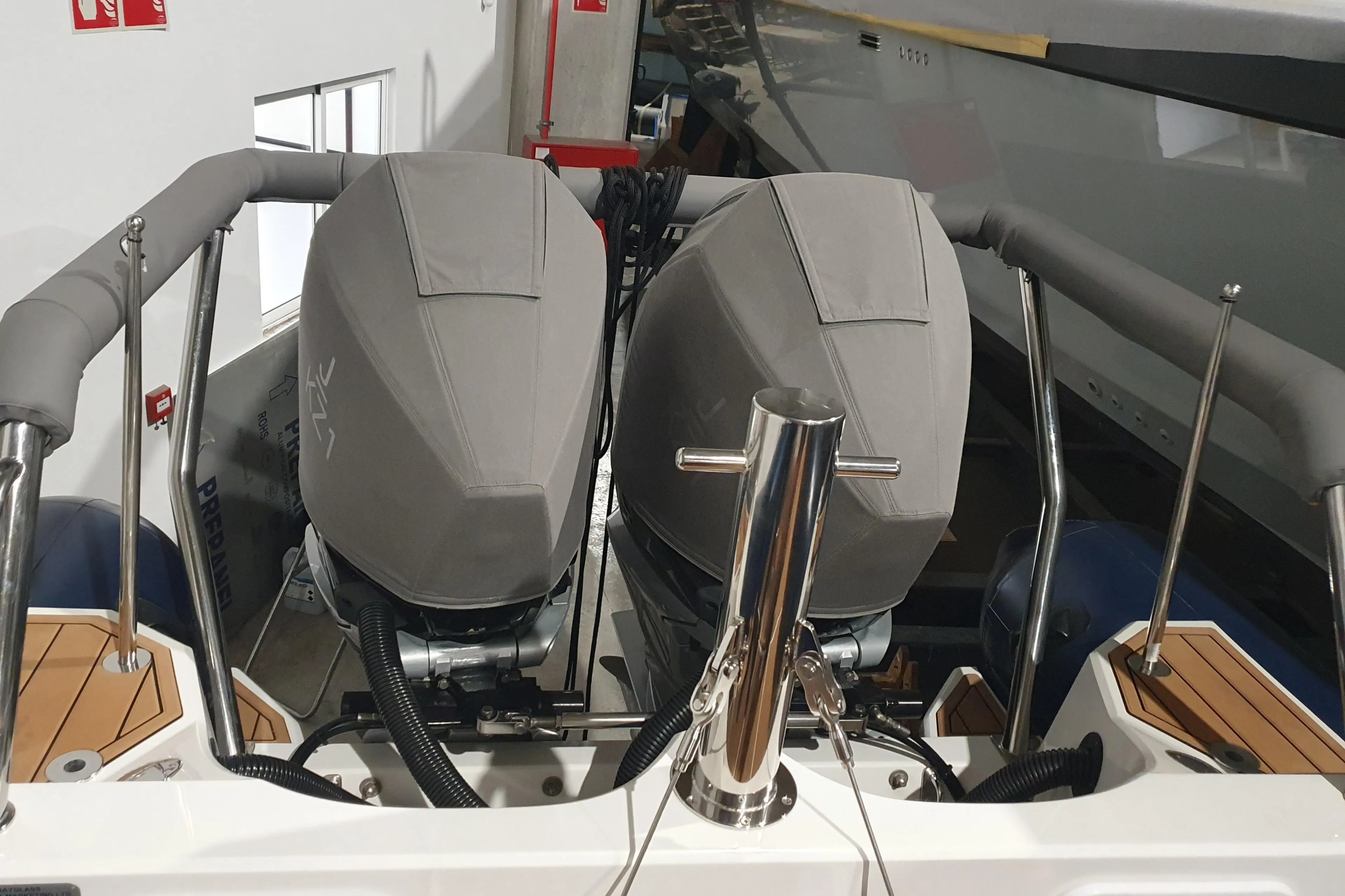 2023 Protector 330 boat with dual covered outboard motors in a storage facility.
