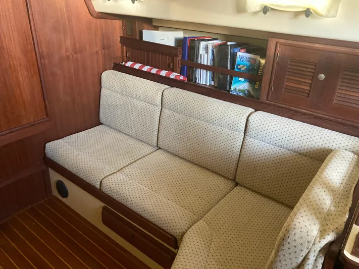 Enabled Yacht Photos Pics Cozy interior of 1999 Island Packet 350 sailboat with cushioned seating and wooden cabinetry.
