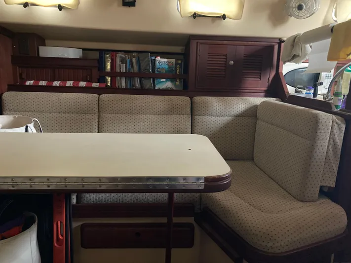 Enabled Yacht Photos Pics Cozy interior of 1999 Island Packet 350 sailboat with cushioned seating and table.