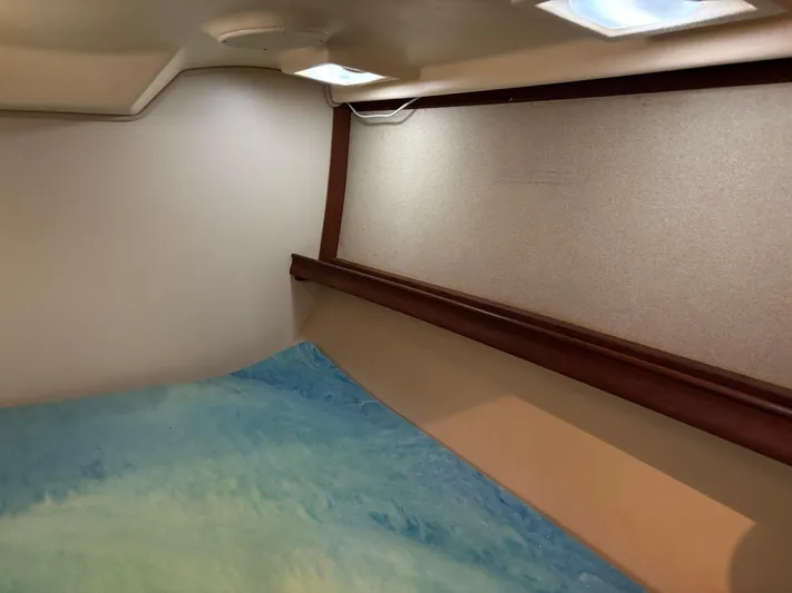 Enabled Yacht Photos Pics Interior cabin of 1999 Island Packet 350 sailboat with blue bedding and wooden trim.