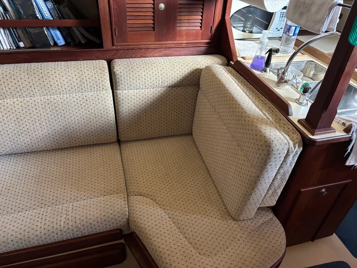 Enabled Yacht Photos Pics Cozy interior of 1999 Island Packet 350 sailboat with cushioned seating and wooden cabinetry.