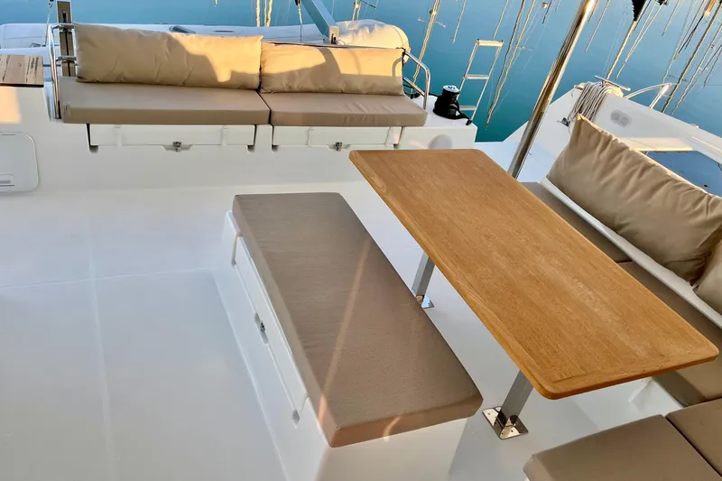 Bright Side Yacht Photos Pics 2018 Fountaine Pajot Saona yacht deck with cushioned seating and wooden table.