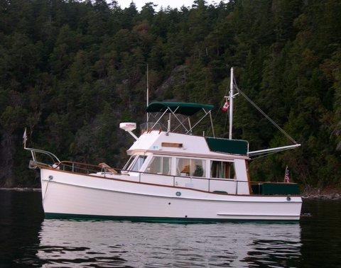 1981 Grand Banks 32 Sedan near forested shoreline.