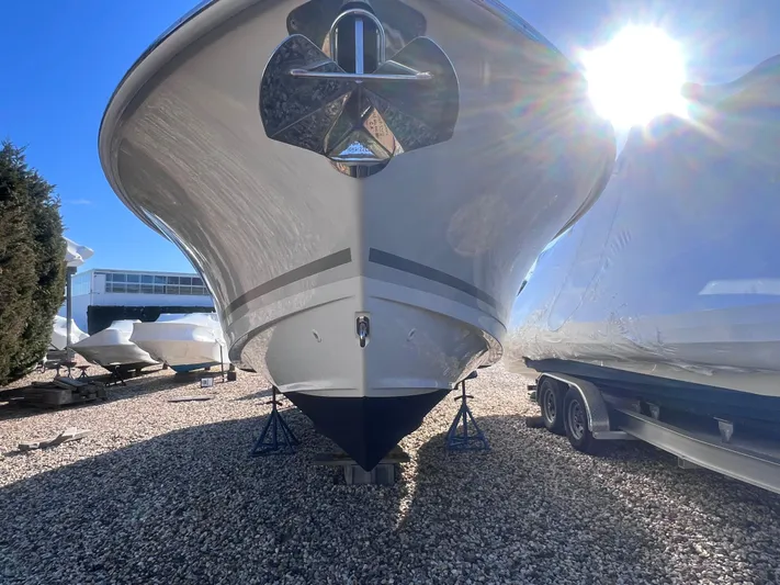  Yacht Photos Pics 2022 Boston Whaler 280 Outrage boat on stands, sunny day, gravel lot.