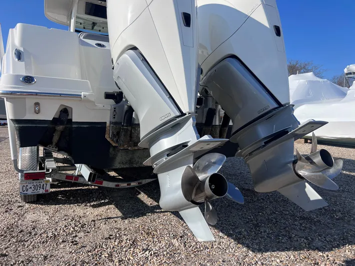  Yacht Photos Pics 2022 Boston Whaler 280 Outrage boat with dual outboard engines on a gravel surface.