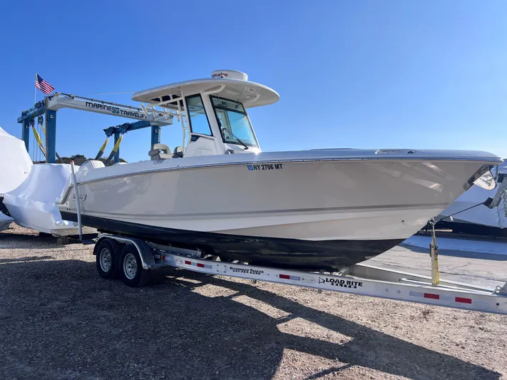  Yacht Photos Pics 2022 Boston Whaler 280 Outrage boat on trailer under clear blue sky.