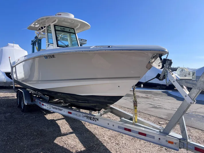  Yacht Photos Pics 2022 Boston Whaler 280 Outrage boat on trailer, side view under clear blue sky.