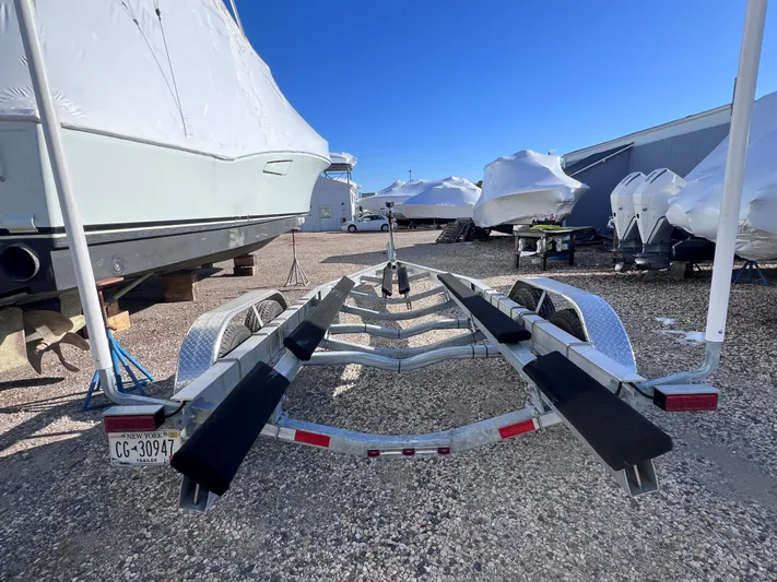  Yacht Photos Pics Boat trailer in storage lot, surrounded by covered boats, clear blue sky above.