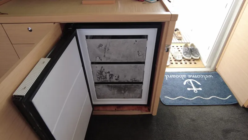  Yacht Photos Pics Open refrigerator on Lagoon 450S yacht, 2019 model, with welcome mat and shoes nearby.