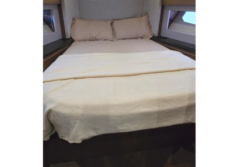  Yacht Photos Pics Luxurious bed in 2022 Monte Carlo MC52 yacht cabin, featuring beige bedding and pillows.