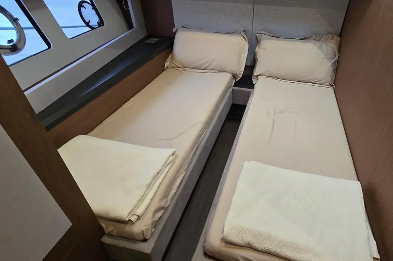  Yacht Photos Pics Twin beds in a 2022 Monte Carlo MC52 yacht cabin with porthole windows.