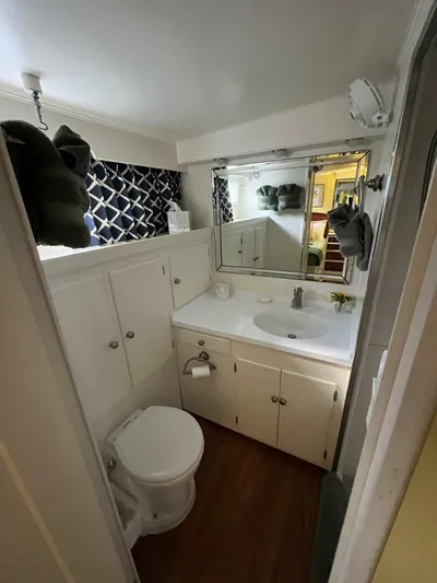 Dovetail Yacht Photos Pics 1972 Trumpy 72 Houseboat bathroom with white cabinets, sink, and toilet.