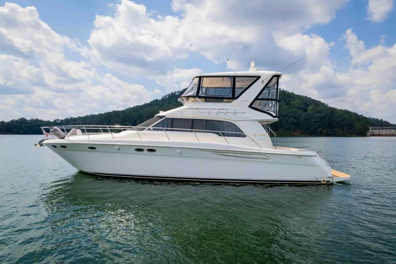  Yacht Photos Pics 1999 Sea Ray 480 Sedan Bridge yacht on calm water under a cloudy sky.