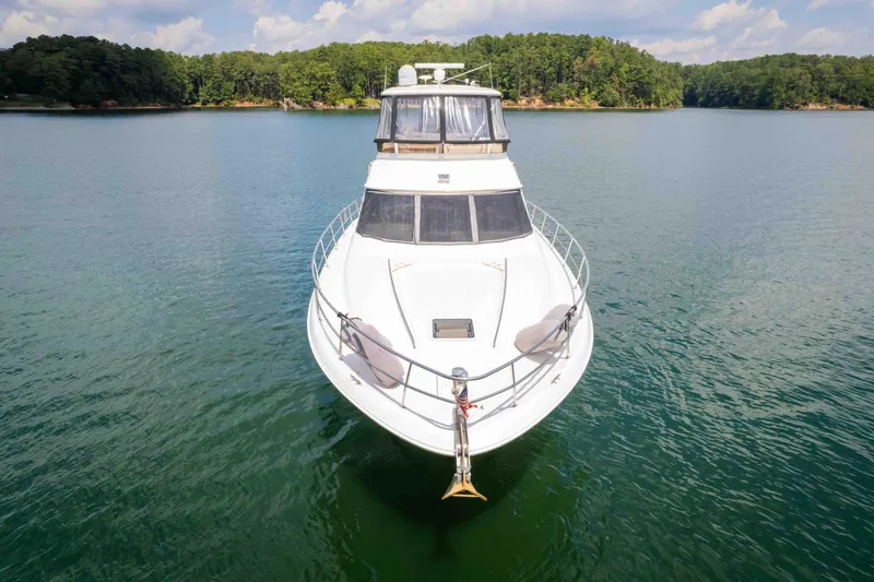  Yacht Photos Pics 1999 Sea Ray 480 Sedan Bridge yacht on serene lake with forested shoreline.