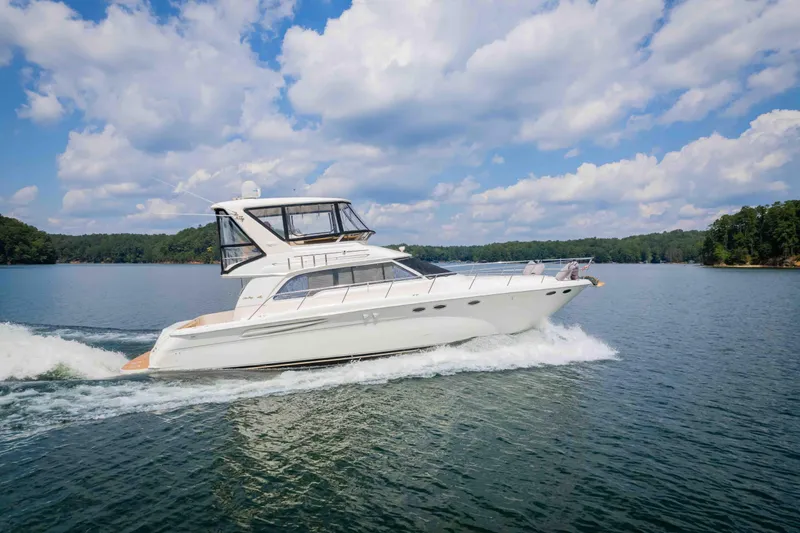  Yacht Photos Pics 1999 Sea Ray 480 Sedan Bridge yacht cruising on a scenic lake under a blue sky.