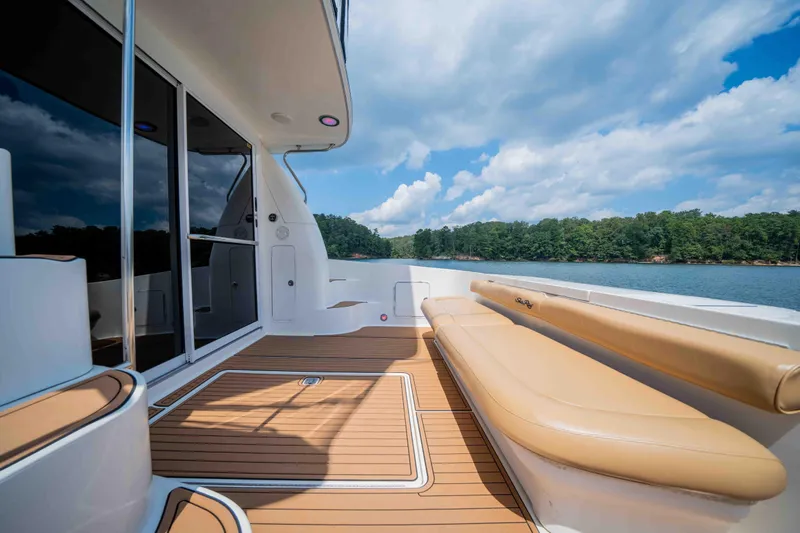  Yacht Photos Pics 1999 Sea Ray 480 Sedan Bridge yacht deck with seating, overlooking serene water and forested shoreline.