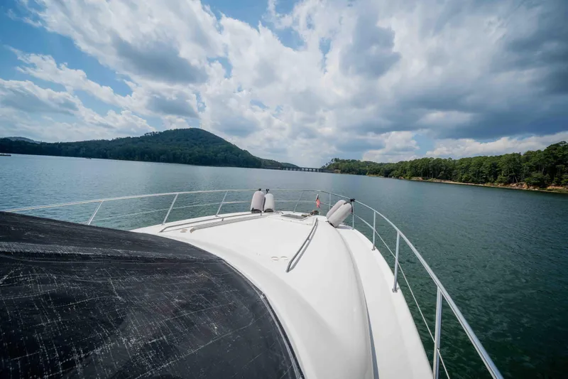  Yacht Photos Pics 1999 Sea Ray 480 Sedan Bridge cruising on a scenic lake under a cloudy sky.