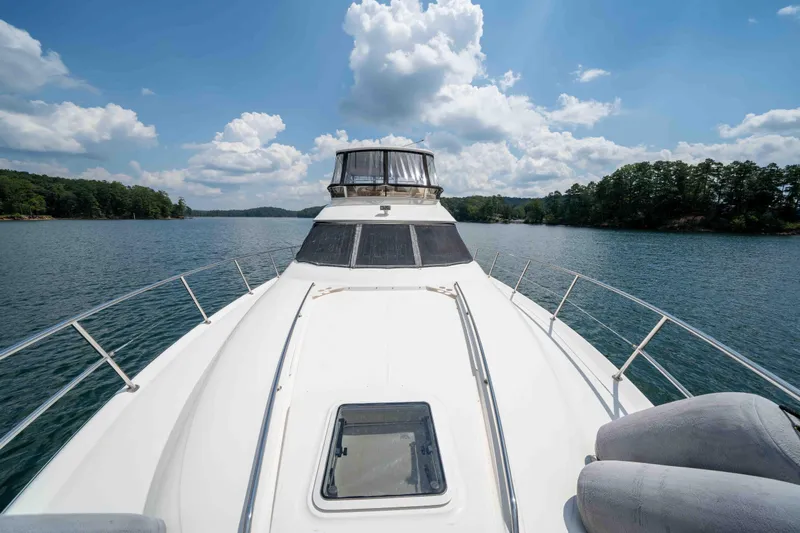 Yacht Photos Pics 1999 Sea Ray 480 Sedan Bridge yacht cruising on a scenic lake under a blue sky.