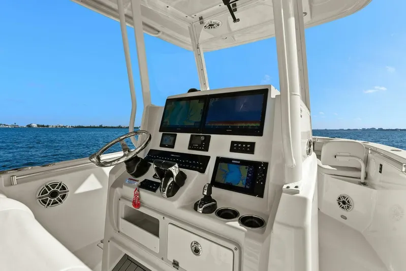  Yacht Photos Pics 2023 Cobia 301 Center Console boat dashboard with navigation screens, steering wheel, and ocean view.