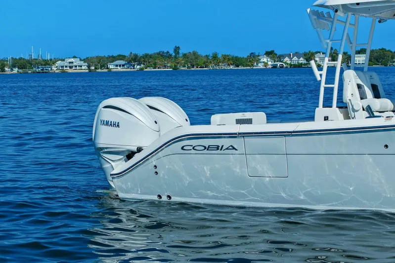  Yacht Photos Pics 2023 Cobia 301 Center Console boat with Yamaha engines on a serene blue water backdrop.