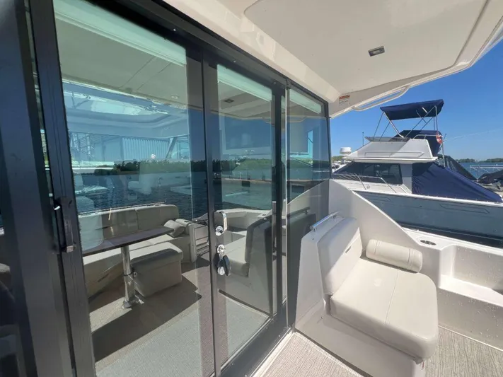  Yacht Photos Pics 2022 Tiara Yachts C44 Coupe with glass doors and outdoor seating on a sunny day.