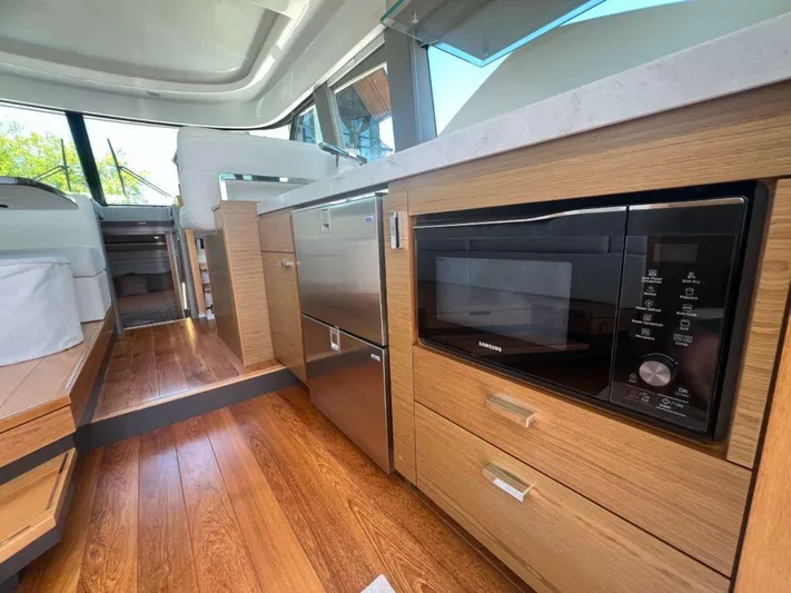  Yacht Photos Pics 2022 Tiara Yachts C44 Coupe interior with modern kitchen, wood flooring, and stainless appliances.