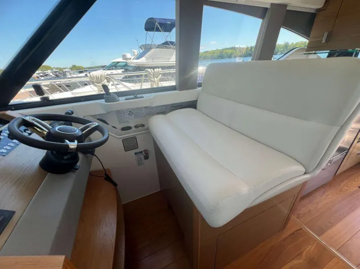  Yacht Photos Pics 2022 Tiara Yachts C44 Coupe interior helm with white seating and steering wheel.