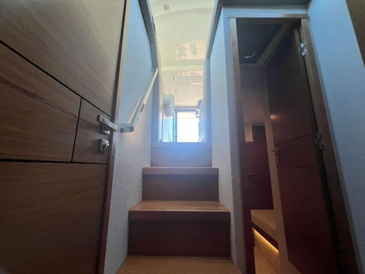  Yacht Photos Pics Staircase inside 2022 Tiara Yachts C44 Coupe, leading to upper deck with wooden finish.