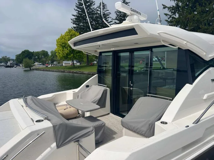  Yacht Photos Pics 2022 Tiara Yachts C44 Coupe with outdoor seating, docked by a scenic lakeside.