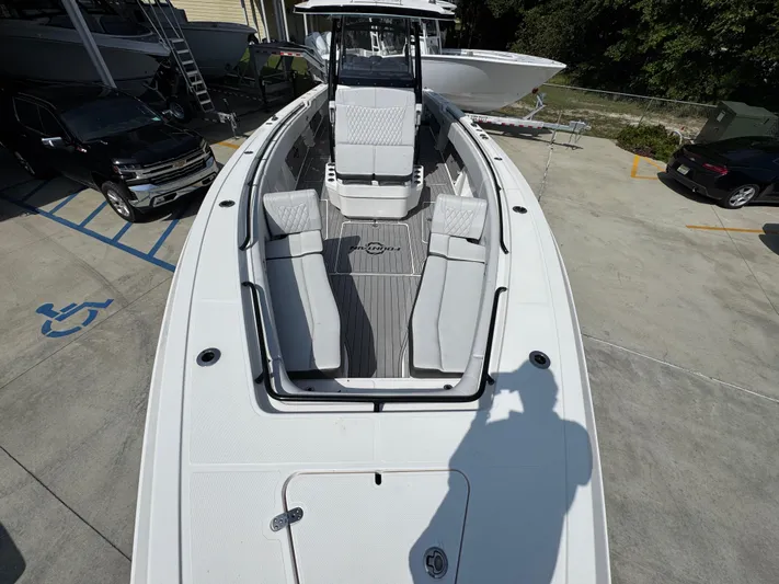  Yacht Photos Pics 2022 Fountain 38TE boat with spacious seating, docked near vehicles in a parking area.