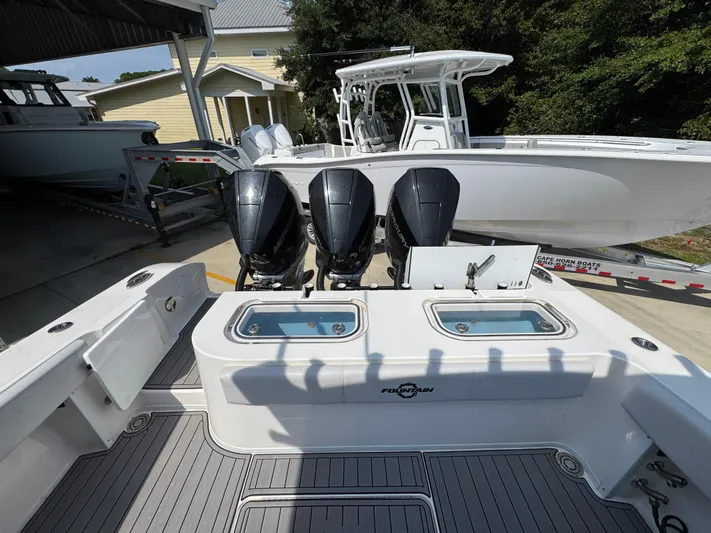  Yacht Photos Pics 2022 Fountain 38TE boat with triple outboard engines, docked near a yellow house.