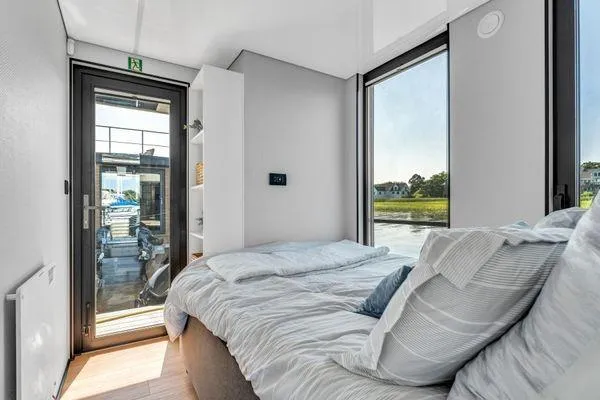  Yacht Photos Pics Modern bedroom in La Mare Modern 11 houseboat, 2024 model, with large windows and cozy bedding.