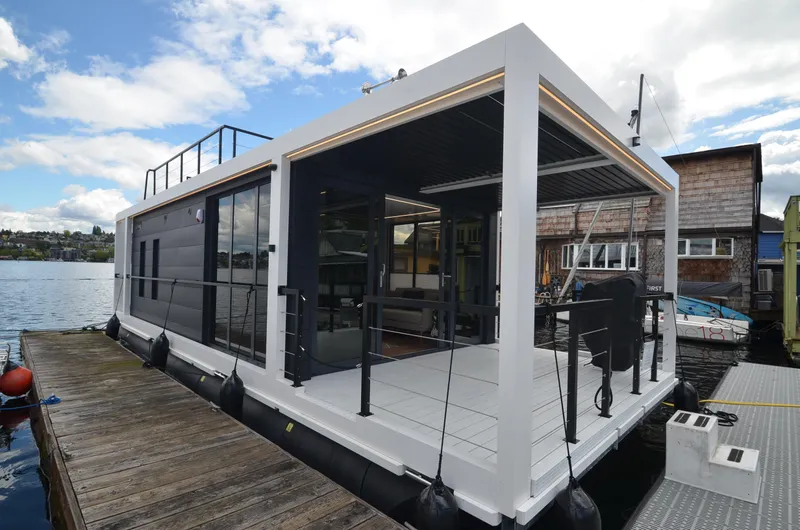  Yacht Photos Pics Modern 2024 La Mare houseboat docked, featuring sleek design and spacious deck area.