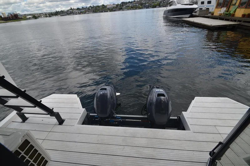  Yacht Photos Pics 2024 La Mare Modern 11 houseboat with dual outboard motors on a serene lake.