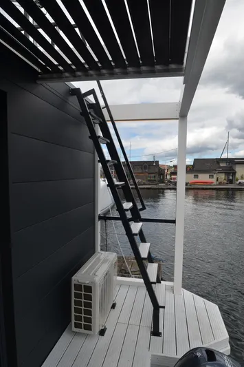  Yacht Photos Pics Modern houseboat with sleek black exterior, stairs, and waterfront view. La Mare Modern 11, 2024.