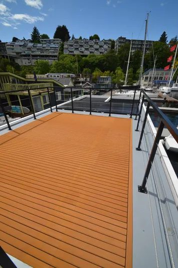  Yacht Photos Pics Modern La Mare 2024 houseboat with spacious deck, overlooking marina and hillside homes.