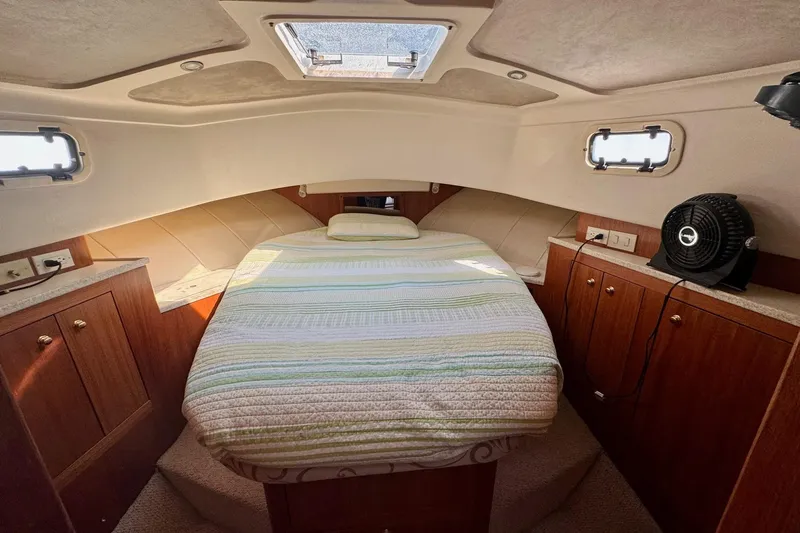 Ripple Yacht Photos Pics Cozy cabin interior of 2000 Mainship 390 Trawler with bed, wood cabinets, and portholes.