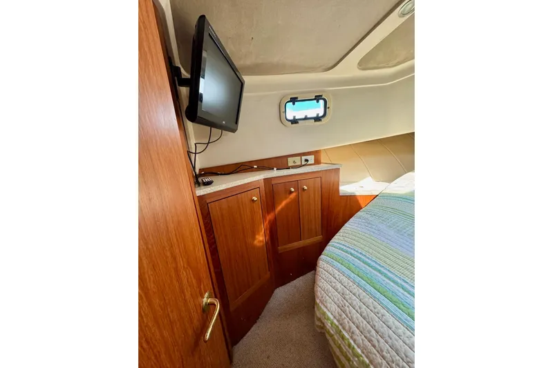 Ripple Yacht Photos Pics 2000 Mainship 390 Trawler cabin interior with TV, wooden cabinets, and bed.