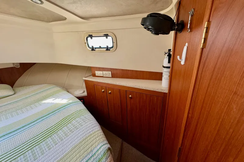 Ripple Yacht Photos Pics Cozy cabin interior of 2000 Mainship 390 Trawler with wood cabinetry and striped bedding.