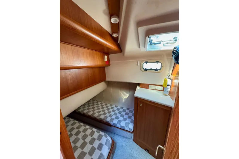 Ripple Yacht Photos Pics 2000 Mainship 390 Trawler cabin with twin beds, wooden cabinetry, and a small window.