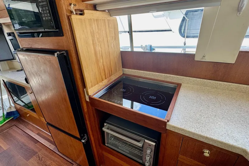 Ripple Yacht Photos Pics 2000 Mainship 390 Trawler kitchen with stove, oven, and wooden cabinetry.