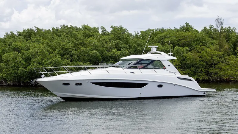  Yacht Photos Pics 2015 Sea Ray 450 Sundancer yacht cruising near lush green shoreline.