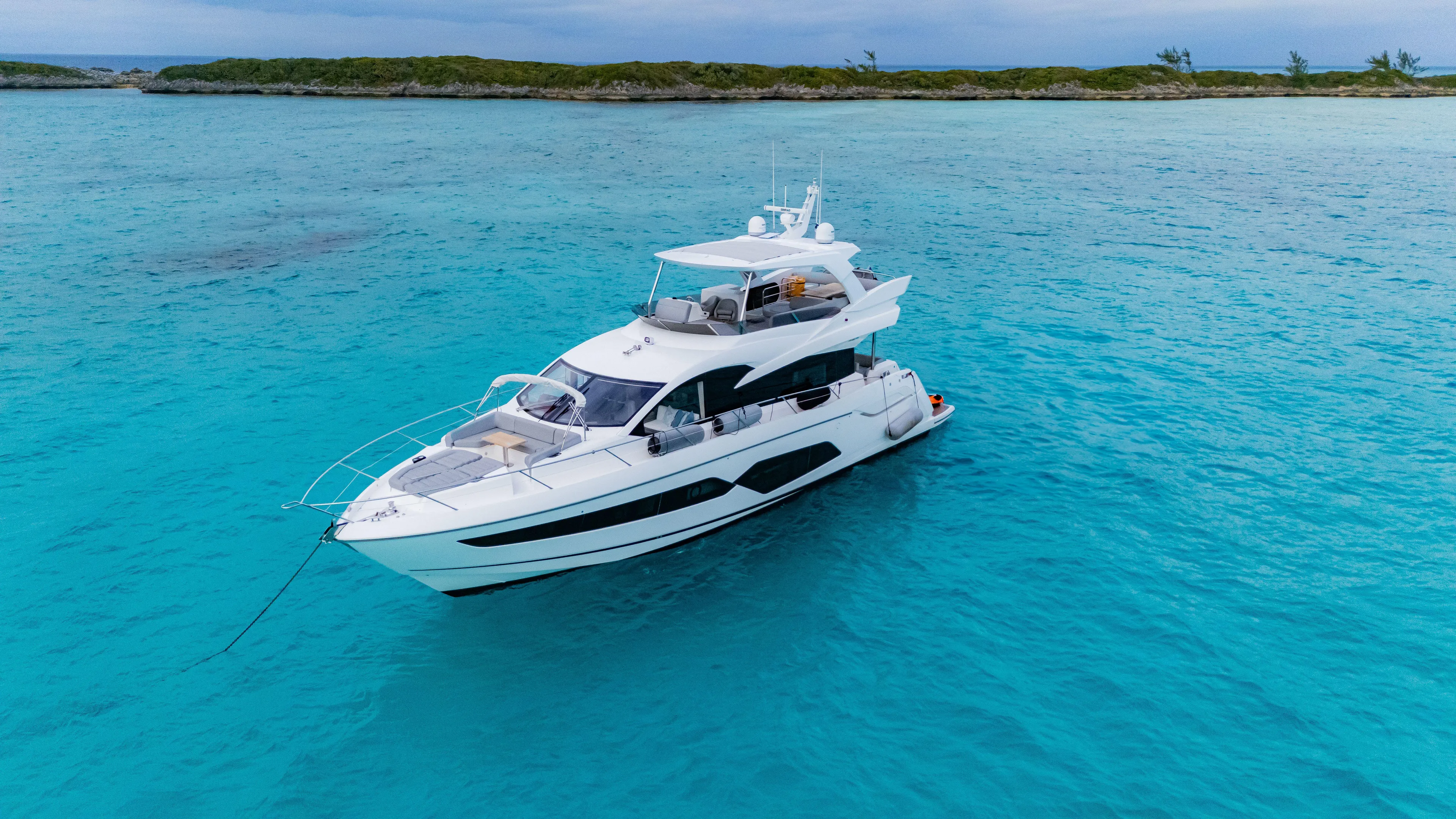 O Legasea Yacht Photos Pics 2018 Sunseeker Manhattan 66 yacht on turquoise waters near a lush island.