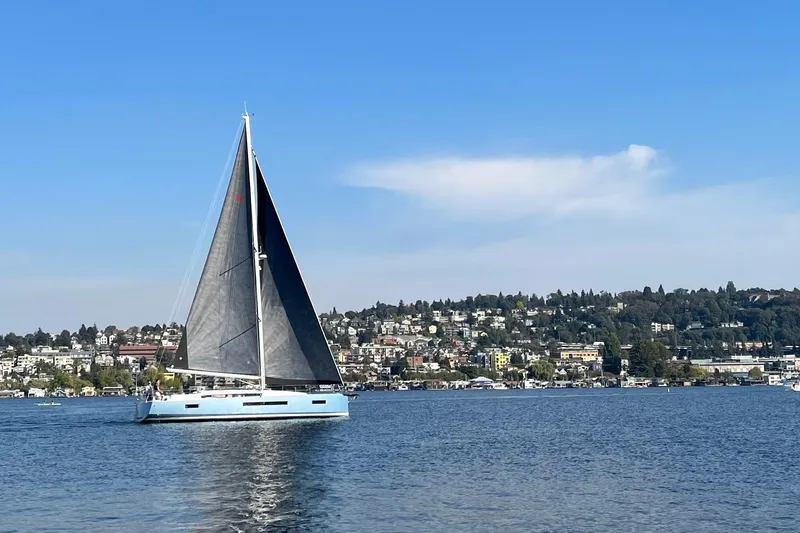 Atticus Yacht Photos Pics 2022 Jeanneau Sun Odyssey 490 sailing on a calm lake with scenic hillside backdrop.