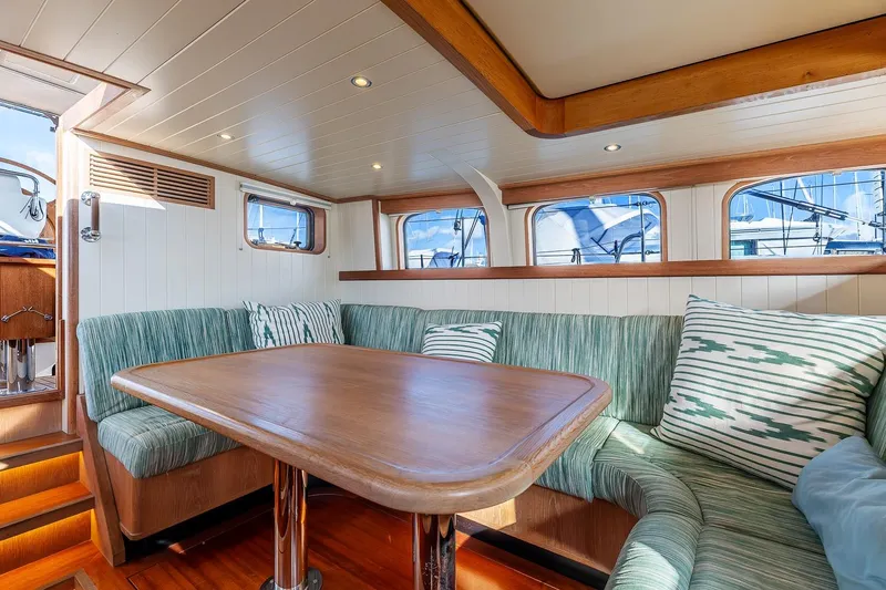 Jaleo Yacht Photos Pics Cozy Puffin 50 yacht interior with wooden table and green cushioned seating, 2019 model.