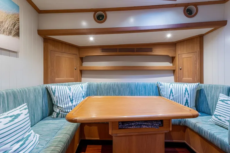 Jaleo Yacht Photos Pics Cozy Puffin 50 yacht interior with wooden table, cushioned seating, and decorative pillows, 2019 model.