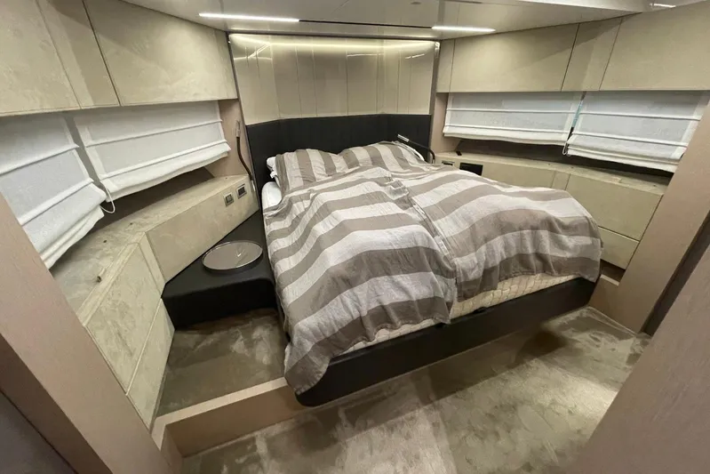  Yacht Photos Pics Luxurious bedroom interior of 2024 Cranchi 67 Sessantasette Fly yacht with striped bedding.