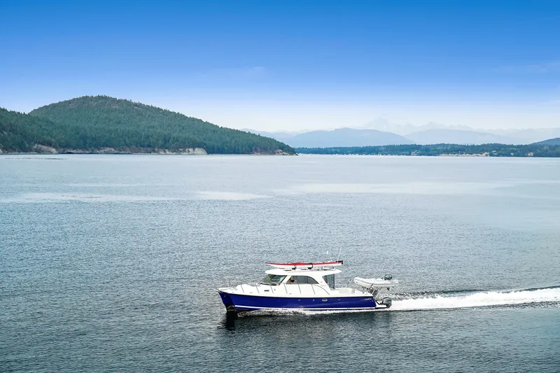  Yacht Photos Pics Aspen C107 boat cruising on a serene lake with forested hills in the background, 2026 model.
